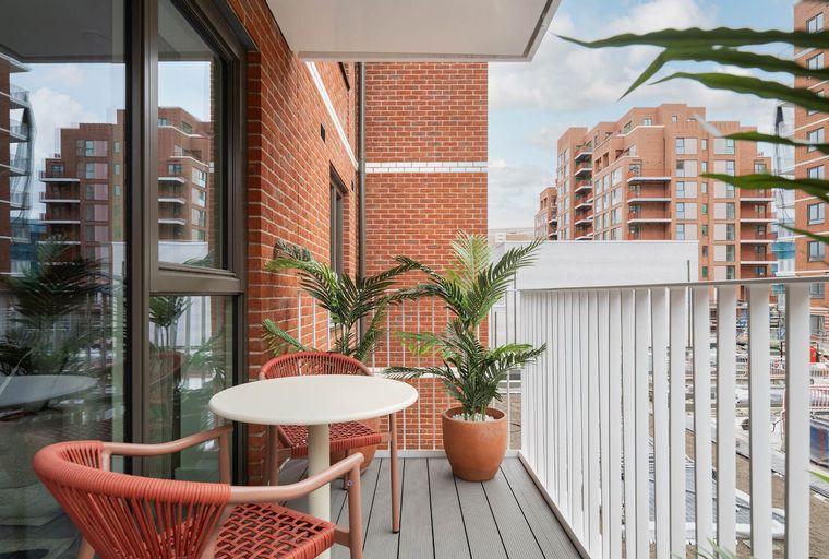 A balcony with a table, chairs, and potted plants.