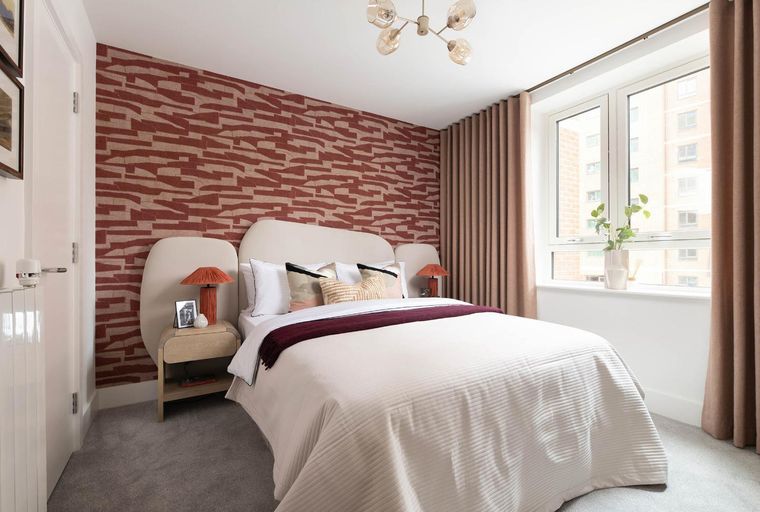 A bedroom with a bed, bedside tables, and a window.