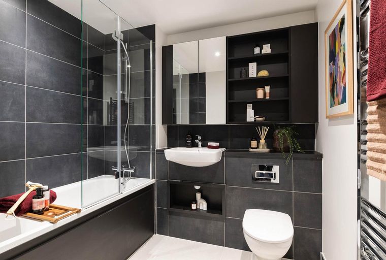 A bathroom with a bathtub, sink, toilet, and shelving.
