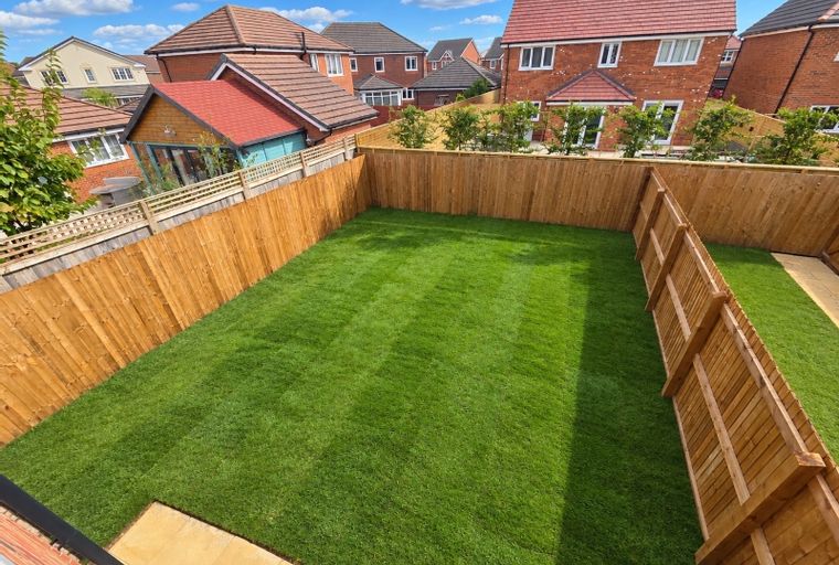 A backyard with a freshly mown lawn and a wooden fence.