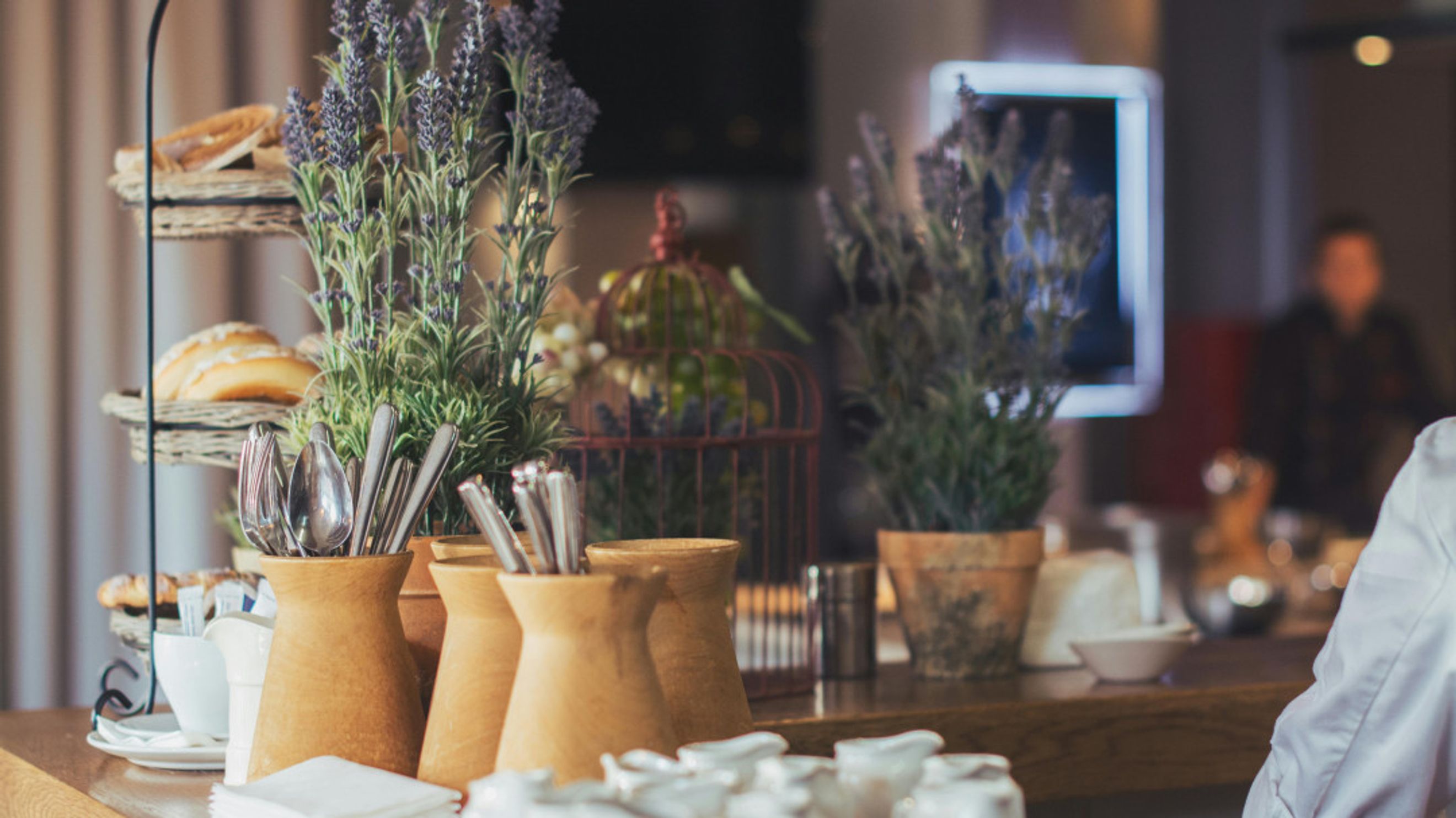 A breakfast buffet with bread, lavender, and silverware in vases.
