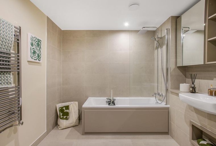 A bathroom with a bathtub, shower, sink, and a heated towel rail.