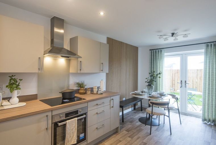 A kitchen and dining area with a stove, cabinets, a round table, and chairs.