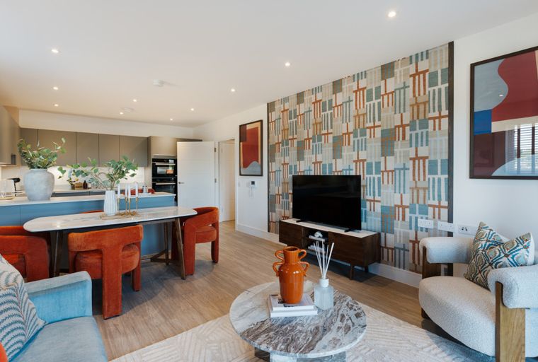 A living room and kitchen area with a dining table, chairs, sofa, television, and kitchen cabinets.