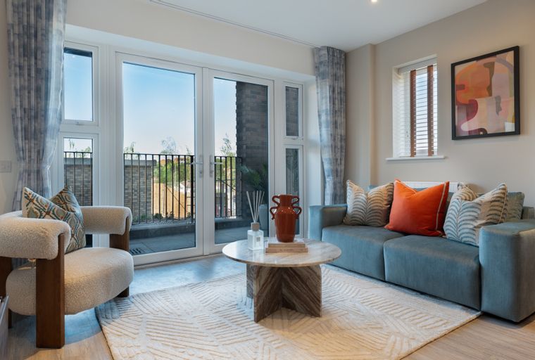 A living room with a sofa, armchair, coffee table, and balcony doors.