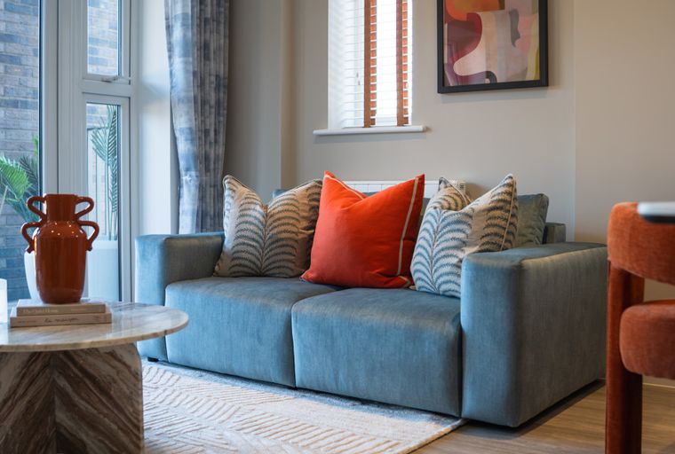 A living room with a blue sofa, decorative pillows, and a marble coffee table.