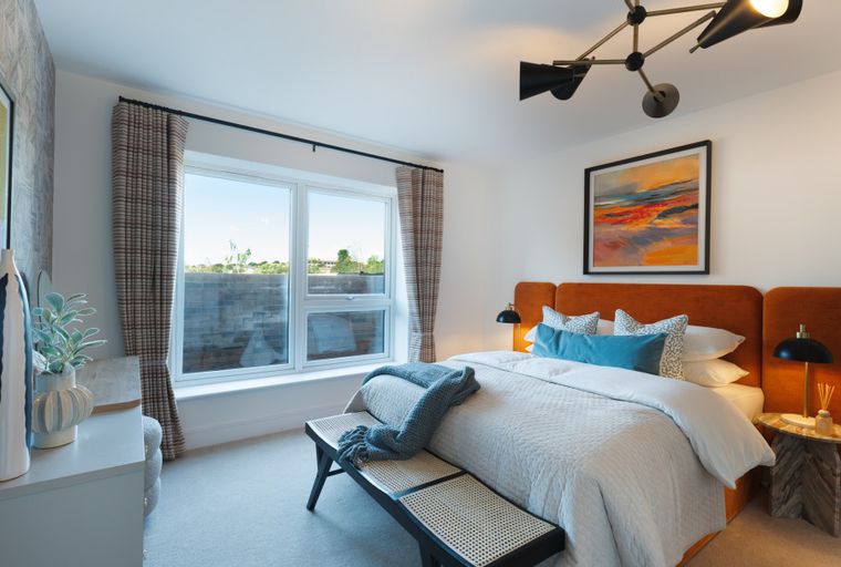 A bedroom with a bed, headboard, bedside table, bench, and window.