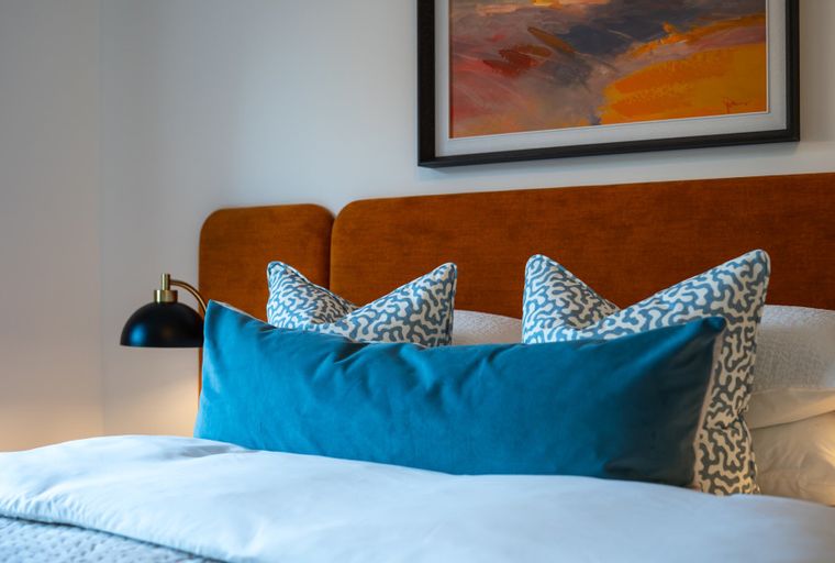 A bedroom with a bed, pillows, and a headboard.
