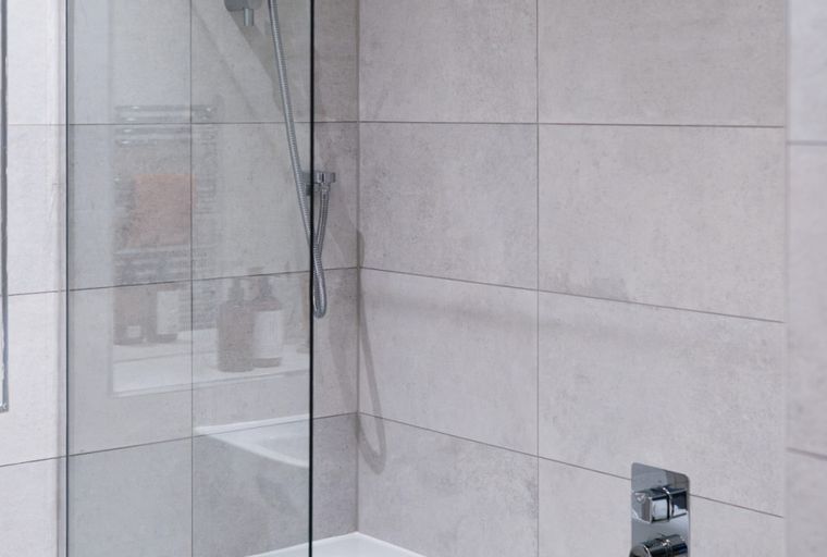 A shower area with tiled walls and a chrome shower head.