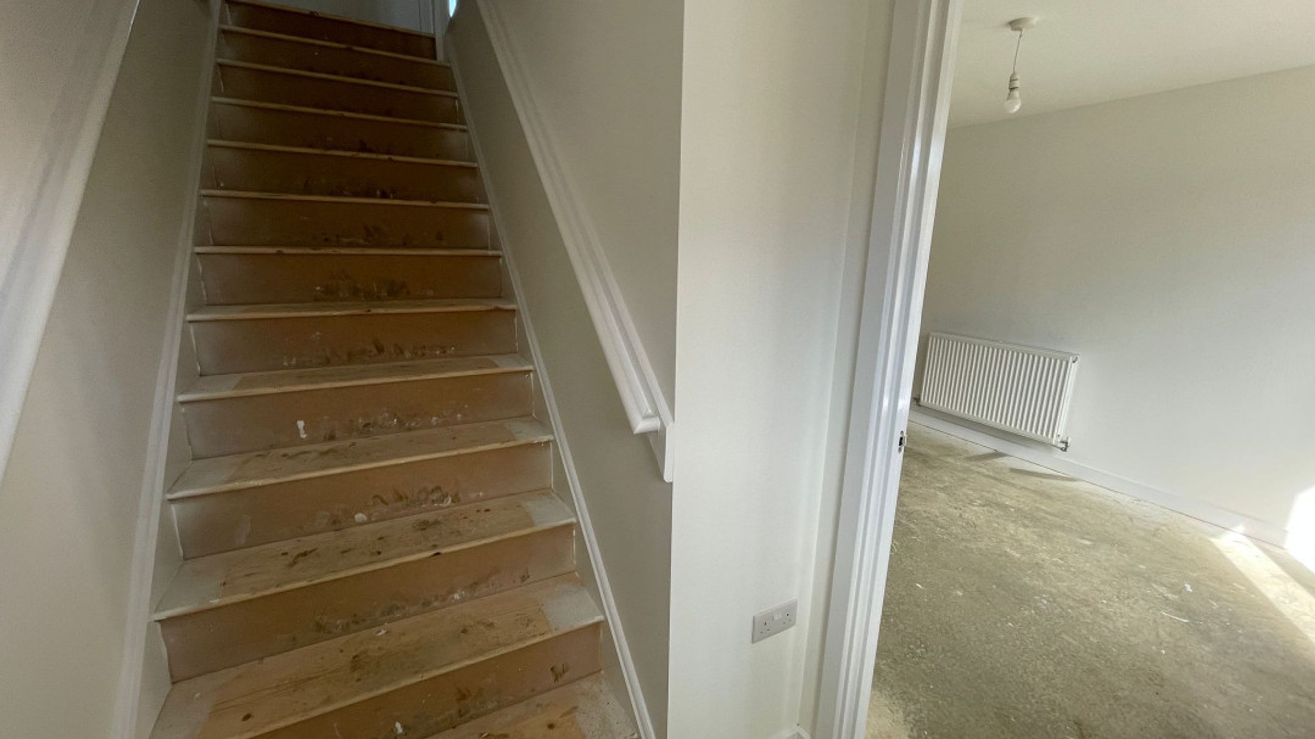 A staircase and a room with a radiator.