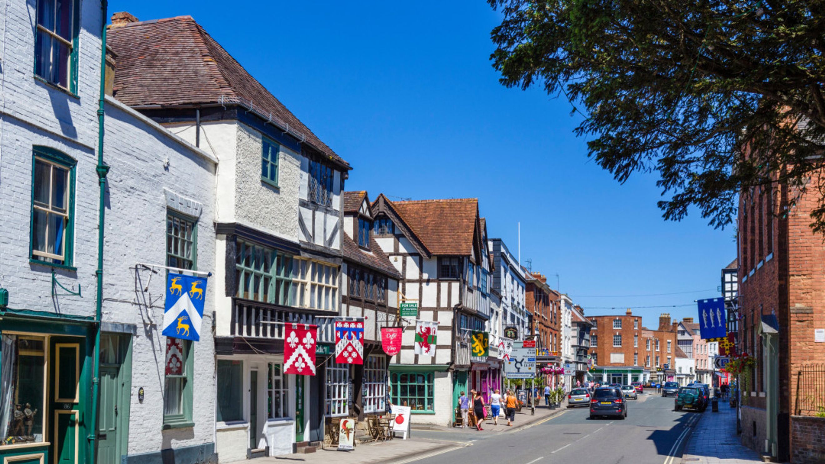 A street lined with historic buildings and shops under a clear blue sky.