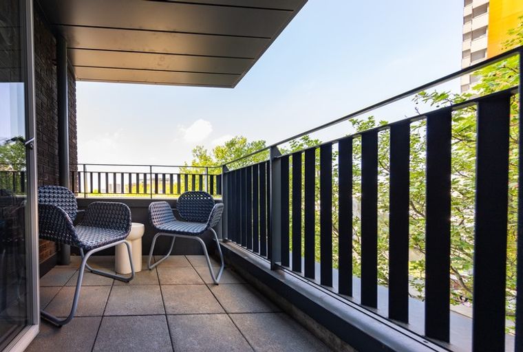 A balcony with two chairs and a side table.