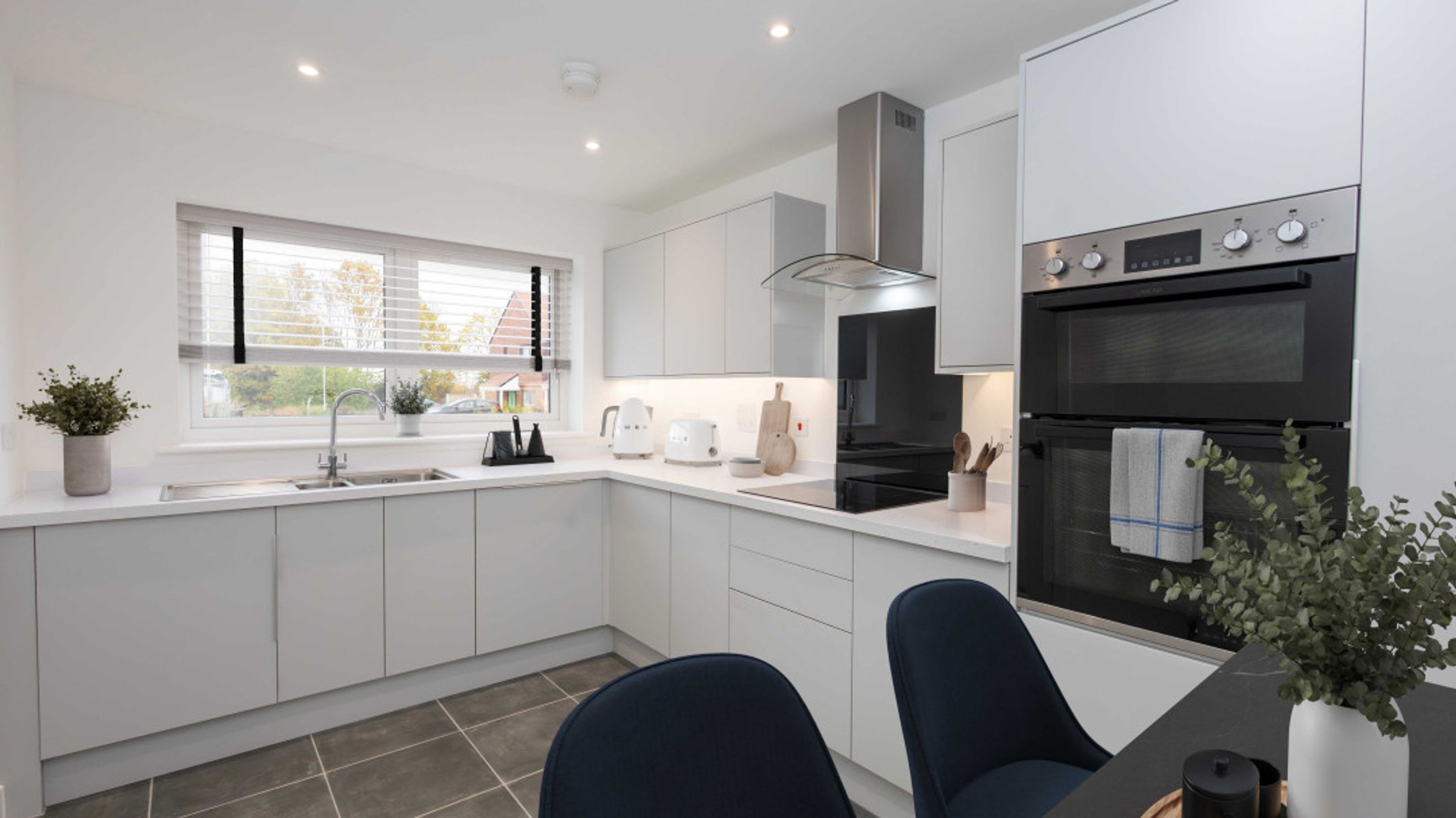 A modern kitchen with light grey cabinets, a sink, and an oven.
