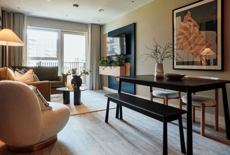A living and dining area with a sofa, armchair, dining table, and a TV unit.