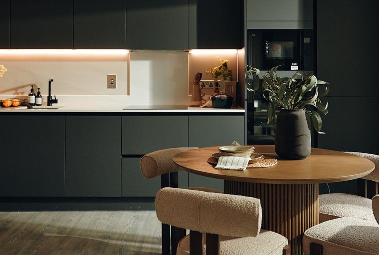 A modern kitchen with dark cabinets, a sink, and a dining table with chairs.