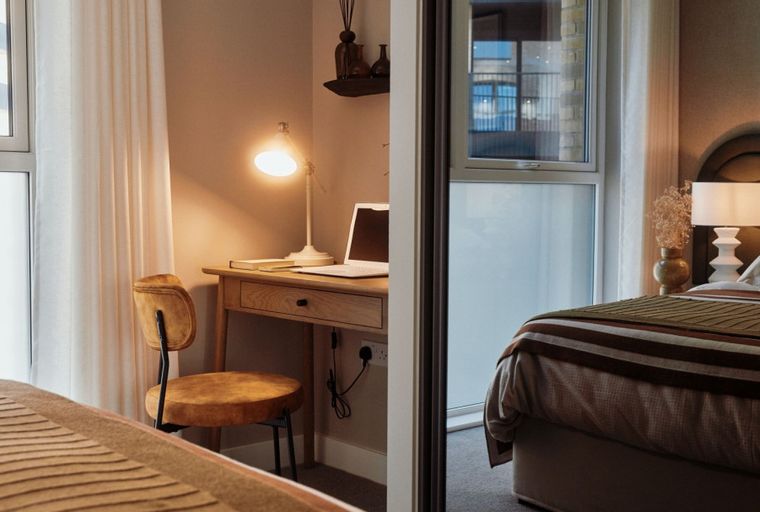 A bedroom and a desk area with a laptop and a chair.