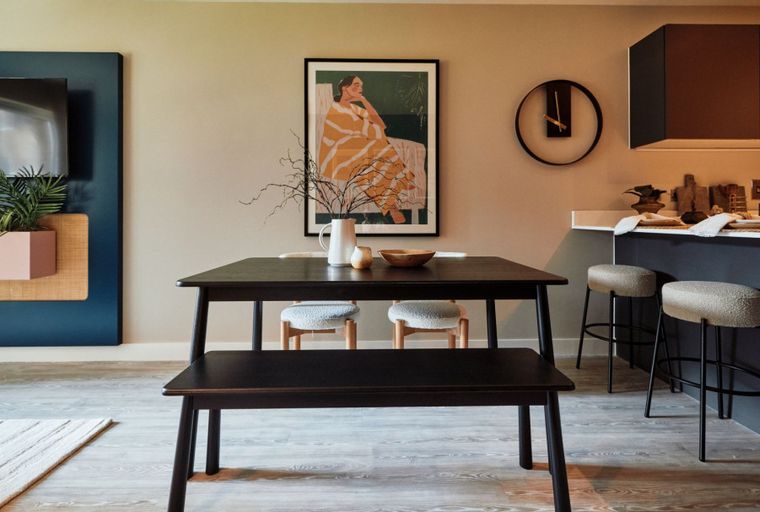 A dining area with a table, bench, chairs, and a kitchen island with bar stools.