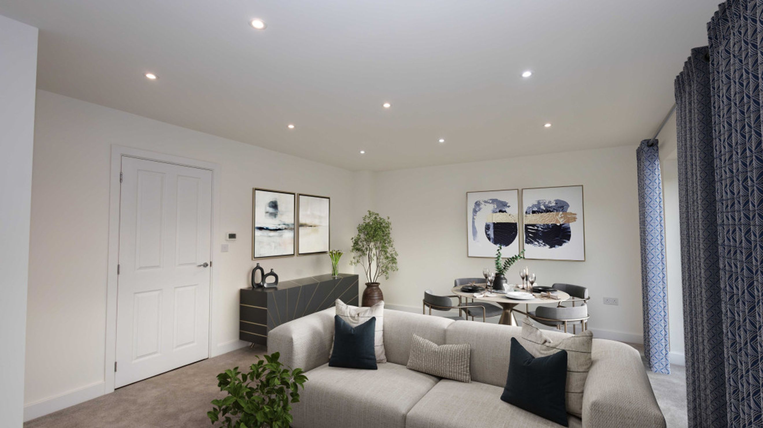 A living and dining room with a sectional sofa, dining table, and abstract art.