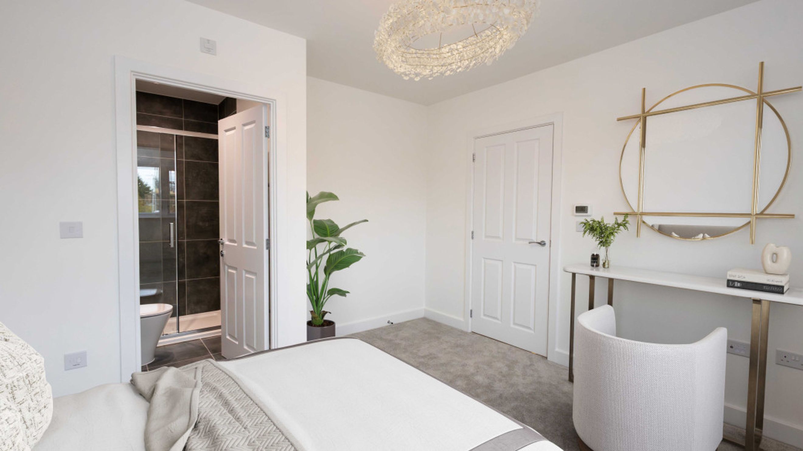 A bedroom with a bed, an en-suite bathroom, a dressing table, and a chair.