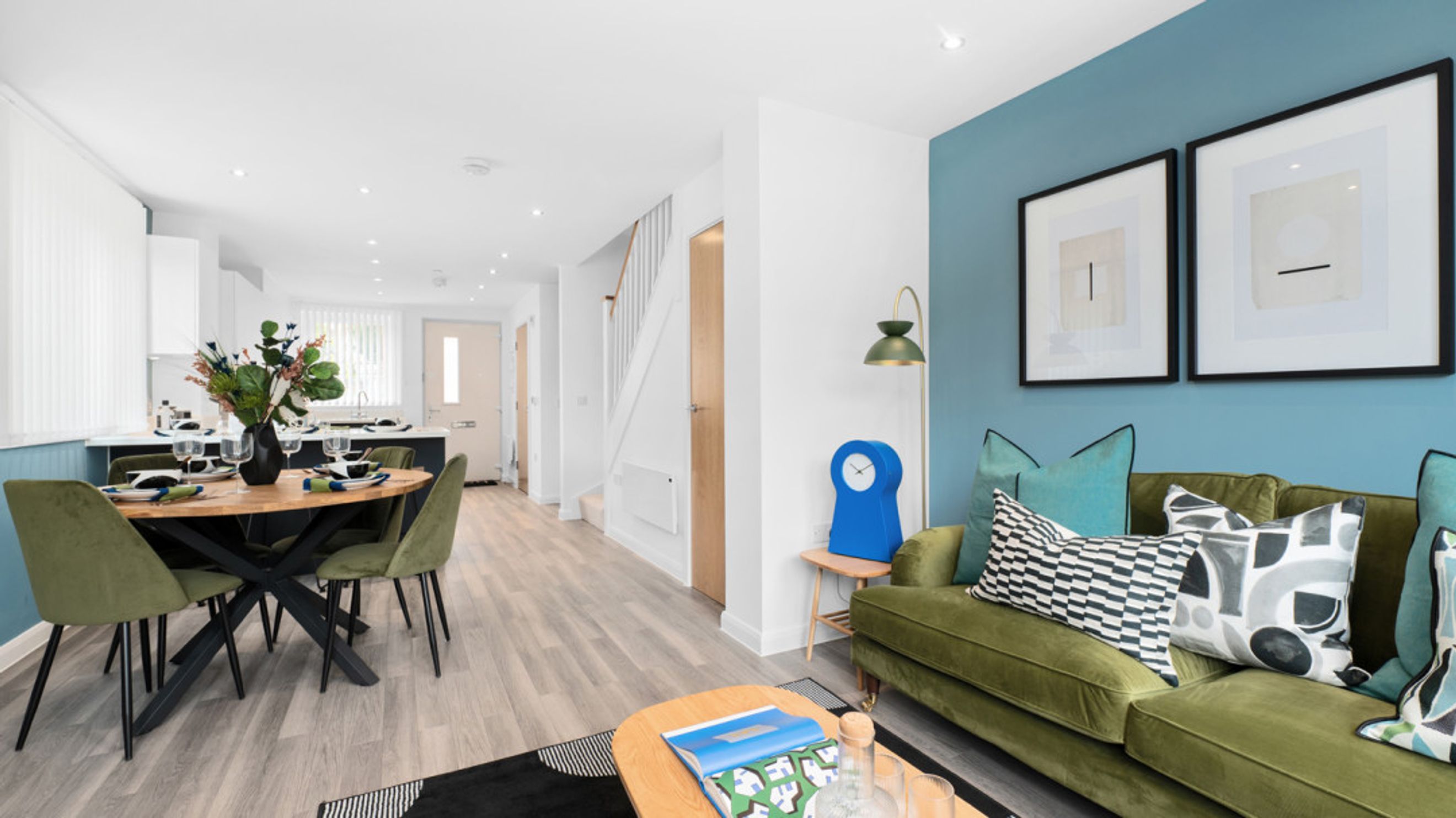 A dining area and living room with green chairs and a green sofa.