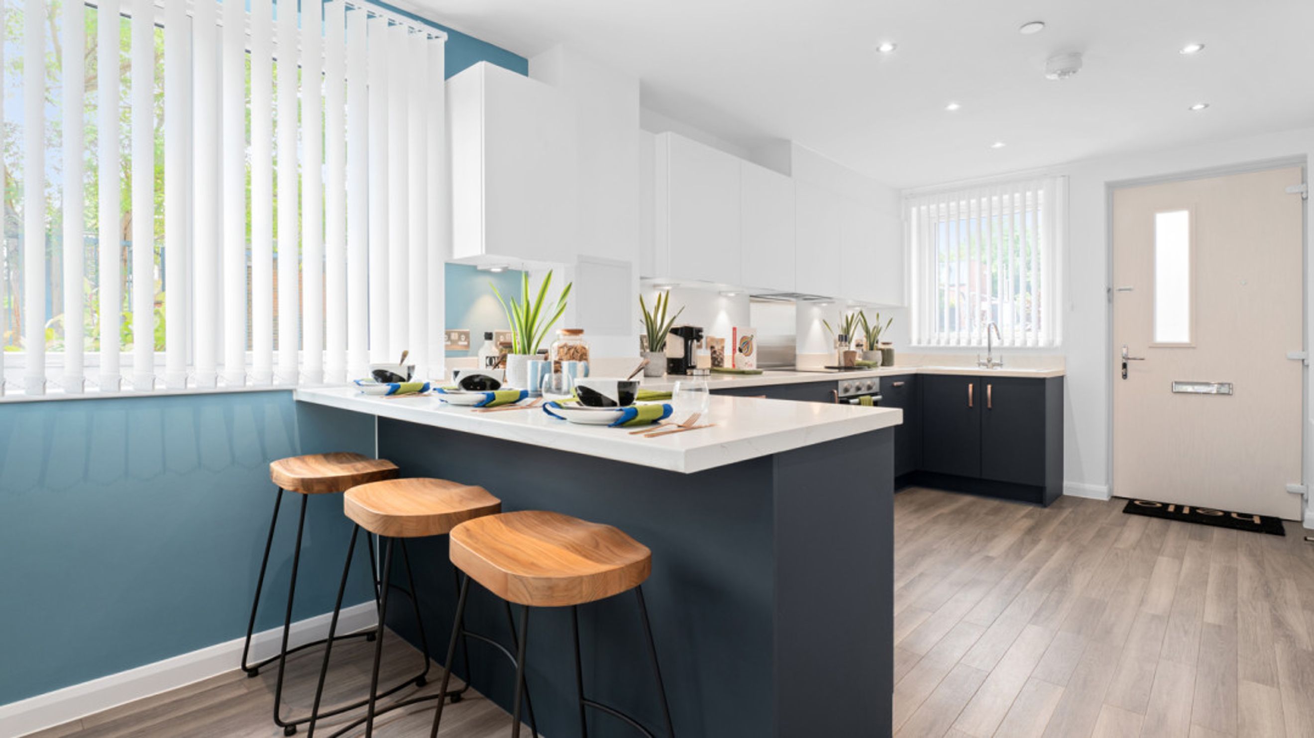 A modern kitchen with an island, bar stools, and white vertical blinds.