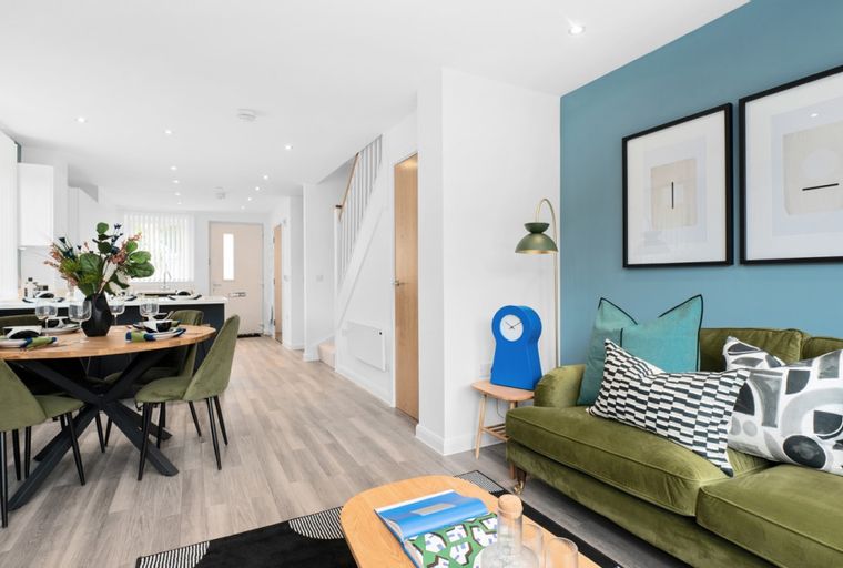 A dining area and living room with a kitchen in the background.