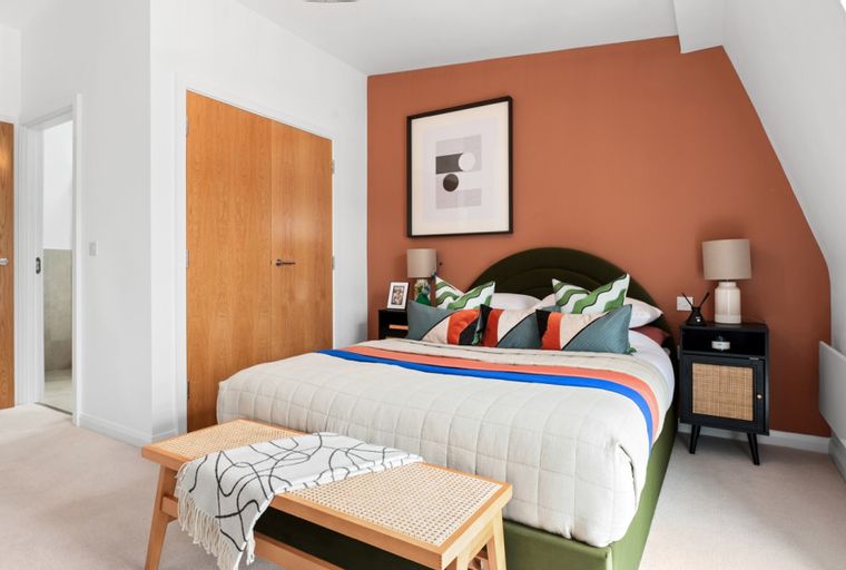 A bedroom with a bed, accent wall, and benches.