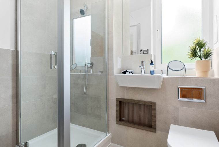 A modern bathroom with a glass shower, sink, and toilet.