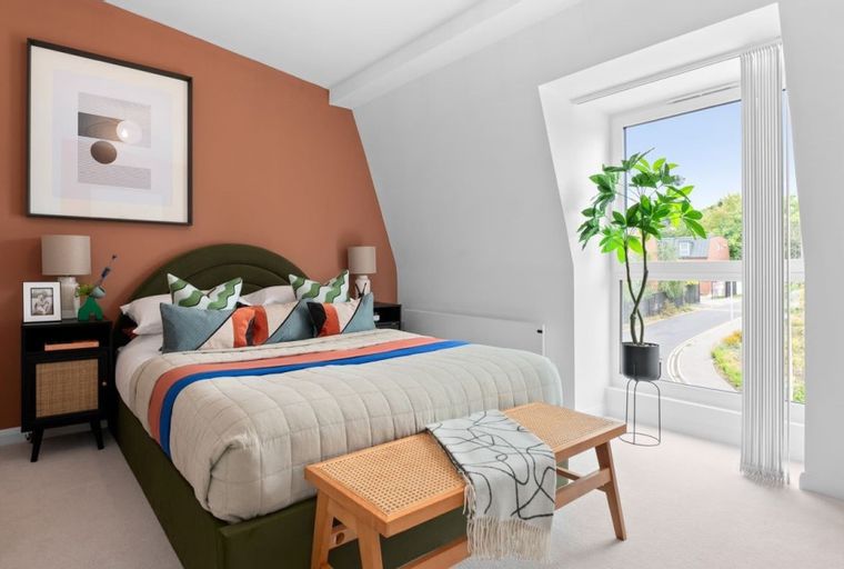 A bedroom with a bed, bedside tables, a bench, and a window.