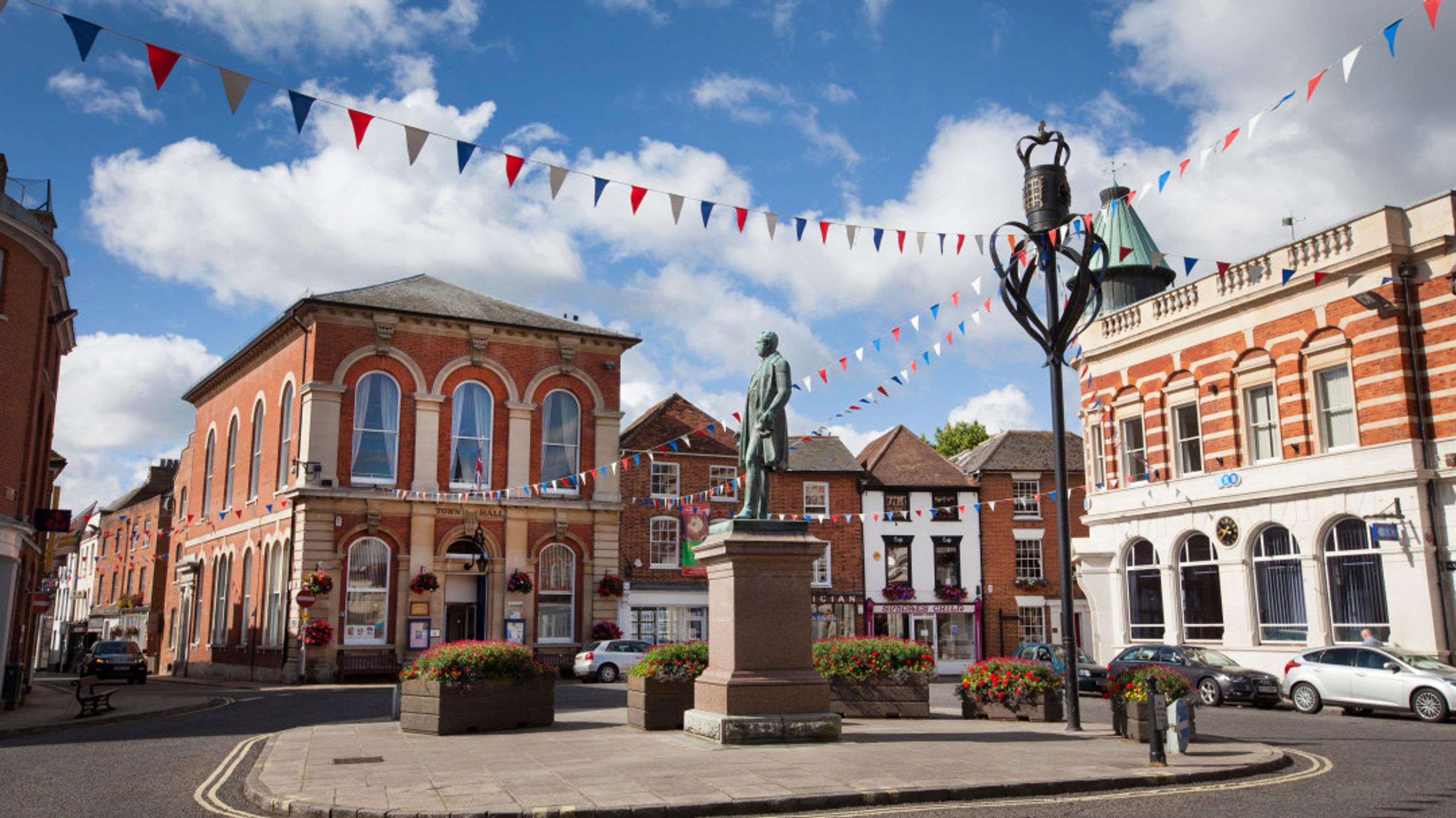 A town square with a statue, buildings, and bunting.