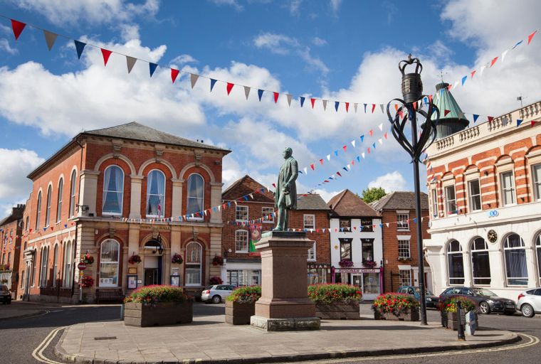A town square with a statue, buildings, and bunting.