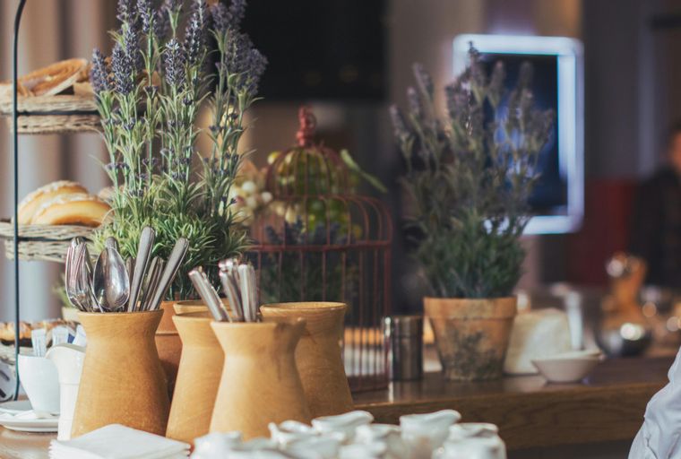 A breakfast buffet with bread, lavender, and silverware in vases.