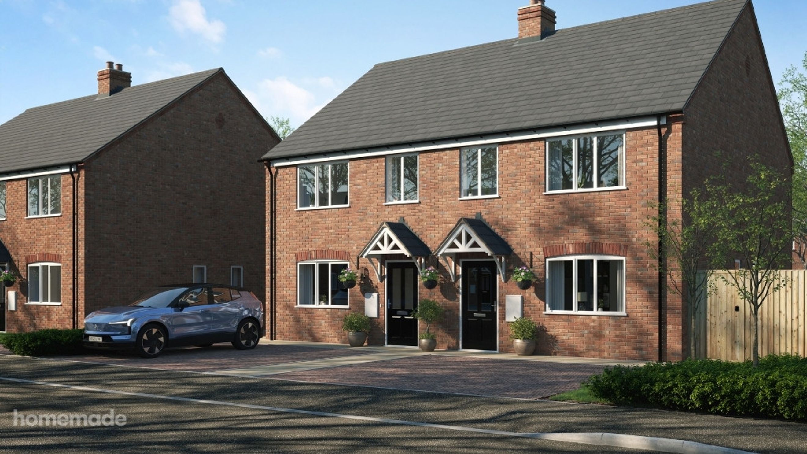 A pair of brick houses with cars parked in front.