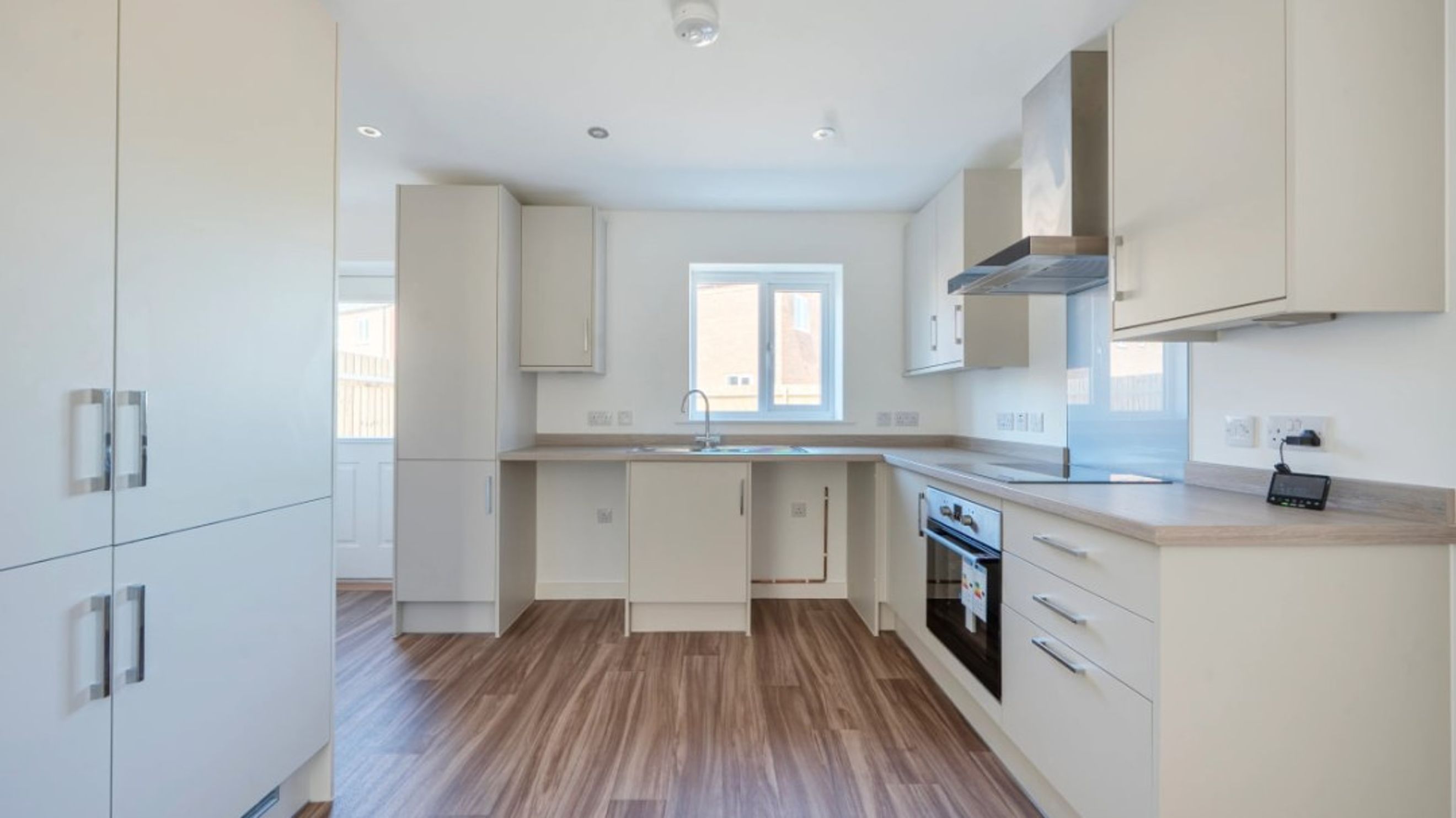 A modern kitchen with white cabinets, a sink, and an oven.