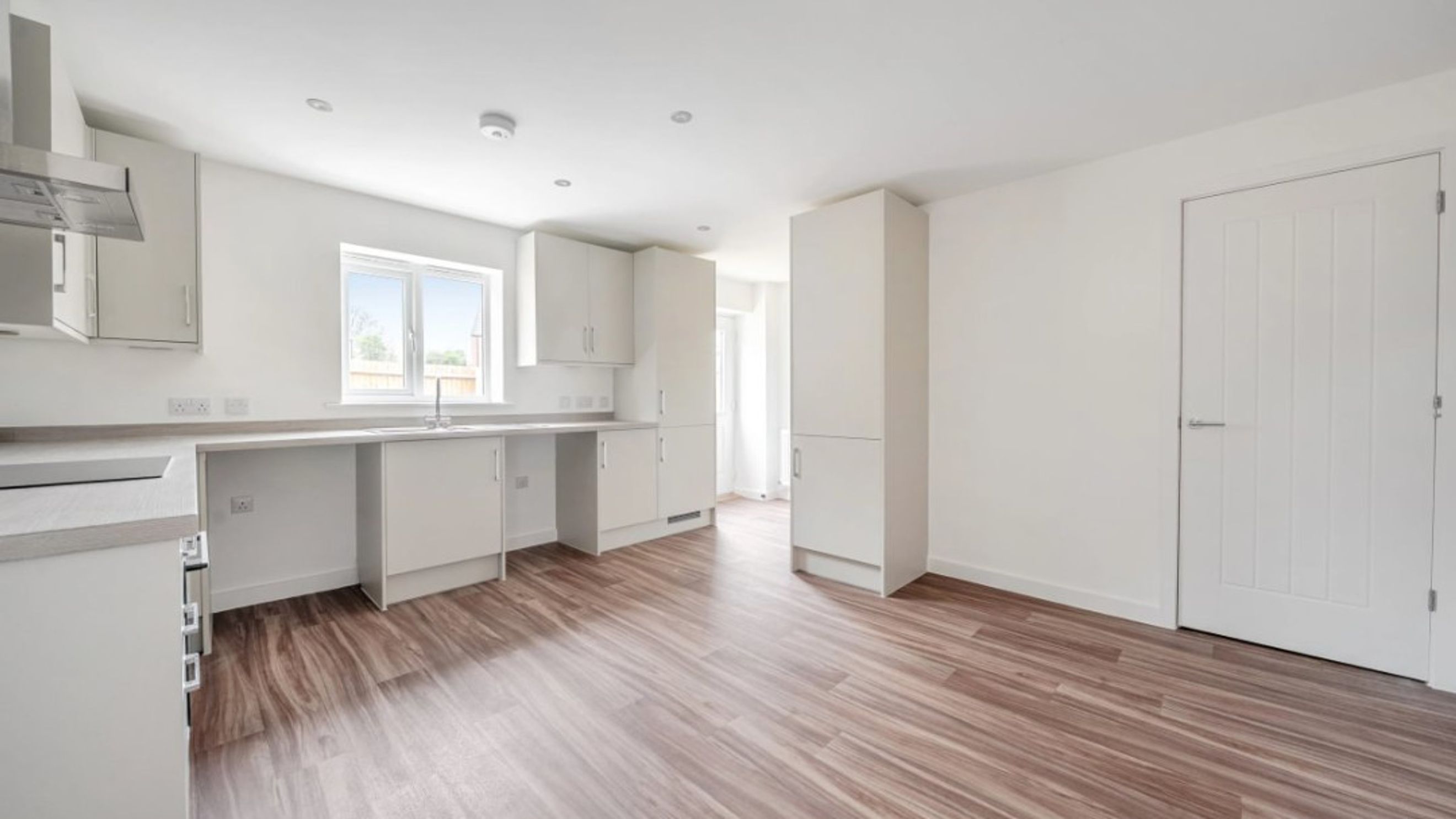 A modern kitchen with white cabinets, a sink, and a window.