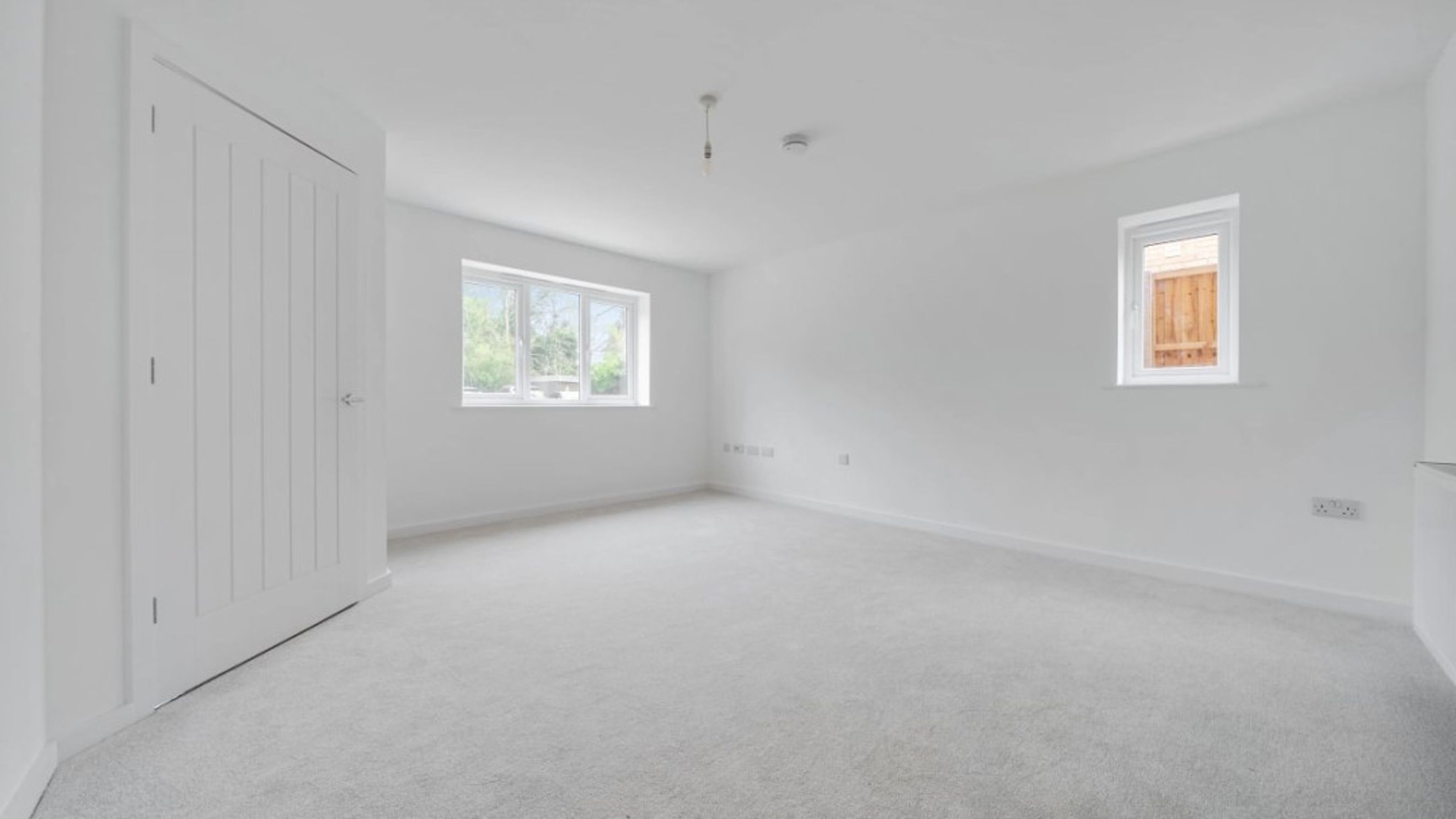 A bedroom with two windows, a closet, and carpeted flooring.