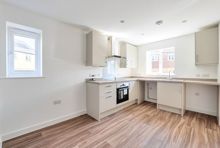 A kitchen with light-colored cabinets, a built-in oven, and a sink.