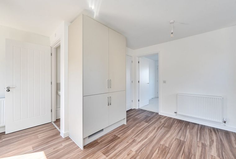 A room with a built-in wardrobe, a radiator, and a white door.