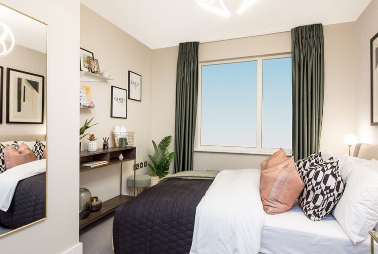 A bedroom with a bed, pillows, curtains, and a window.