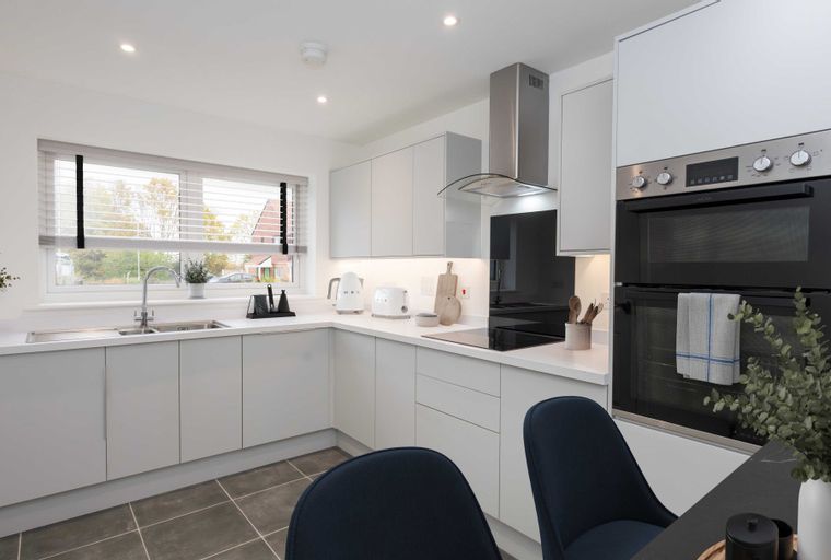 A modern kitchen with light grey cabinets, a sink, and an oven.