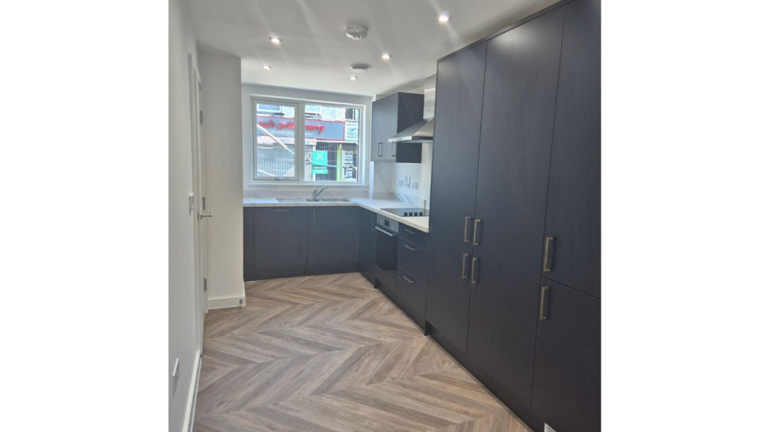 A modern kitchen with dark cabinets, a sink, and a window.