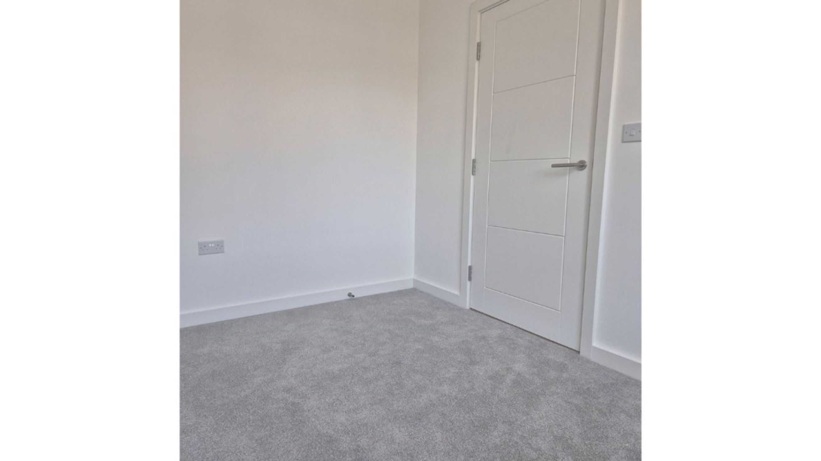 A room with grey carpet and a white door.