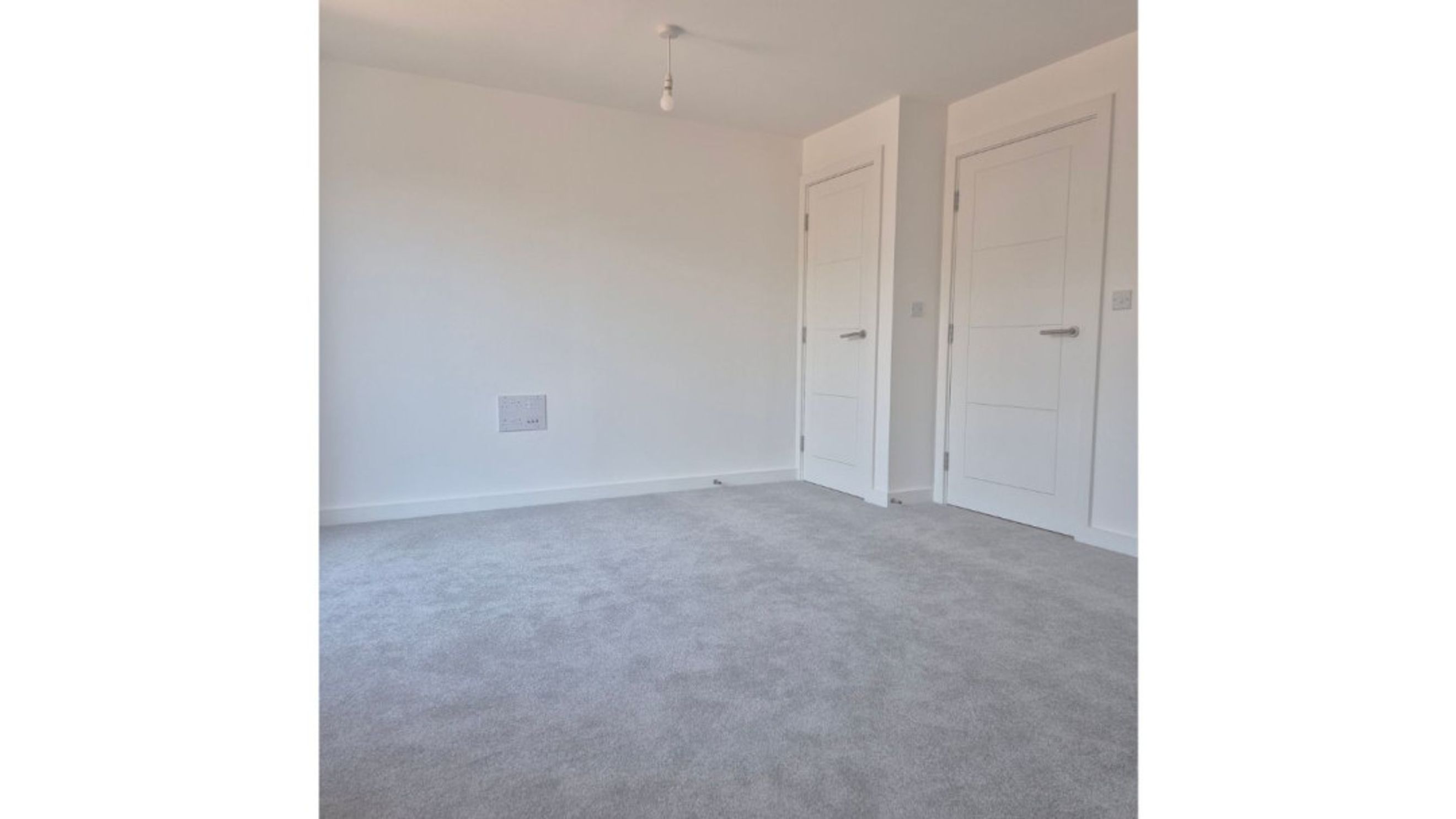 A room with two white doors and a grey carpet.