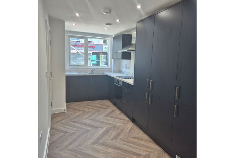 A modern kitchen with dark cabinets, a sink, and a window.