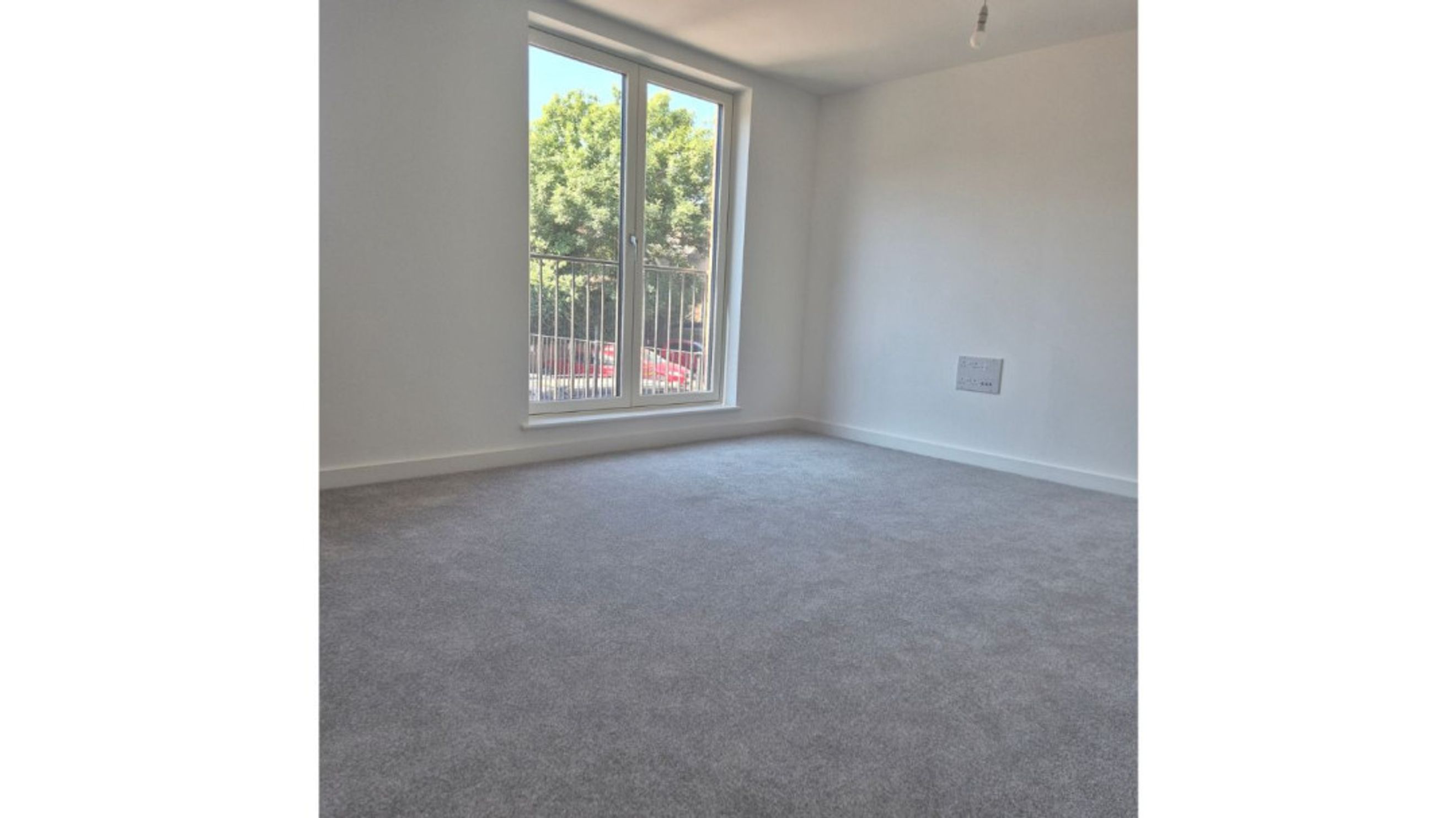 A room with grey carpet and a large window.