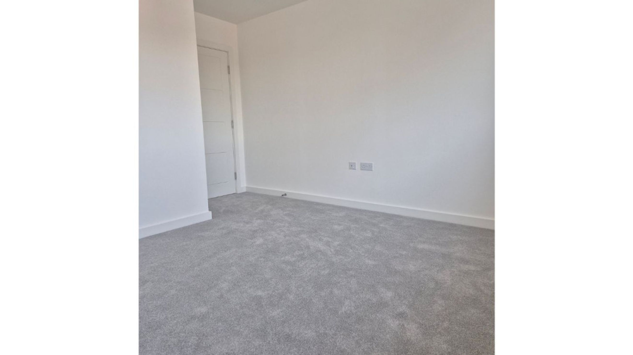 A room with grey carpet and a white door.