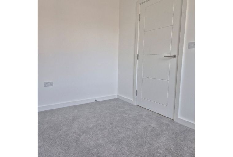 A room with grey carpet and a white door.