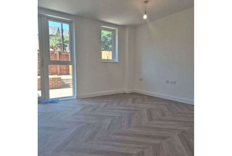 A room with a herringbone floor, a window, and glass doors leading outside.