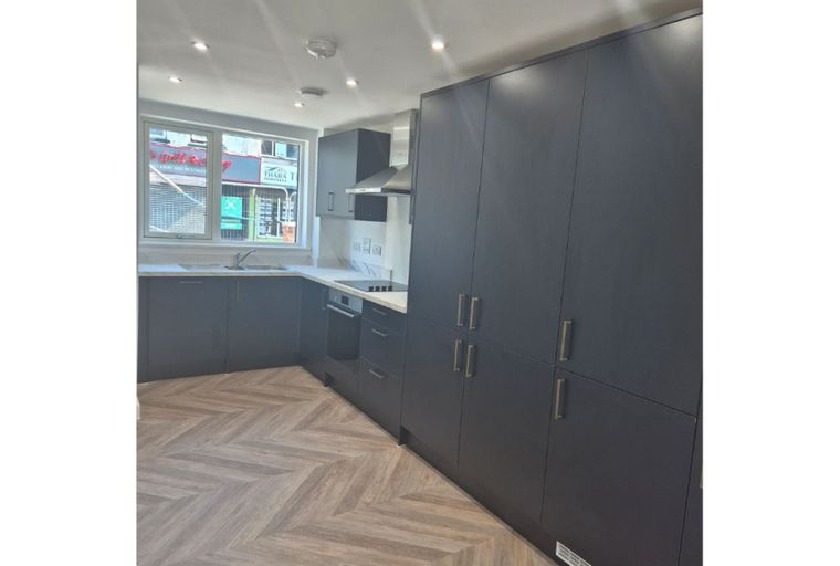 A modern kitchen with dark cabinets, a herringbone floor, and a window.