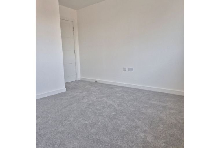 A room with grey carpet and a white door.